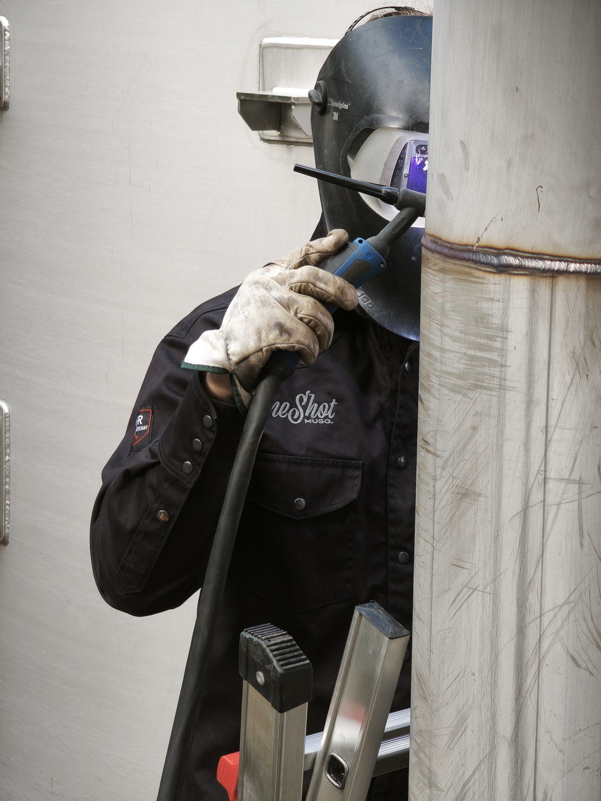 Welding a pipeline, standing on a ladder