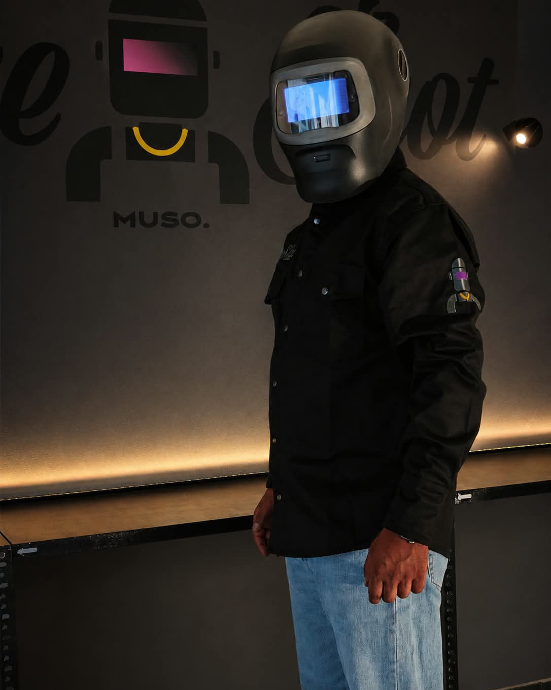 La OneShot FR Jacket OFFICINA 01 di profilo, con il casco ricamato sulla manica, indossata da MUSO in officina